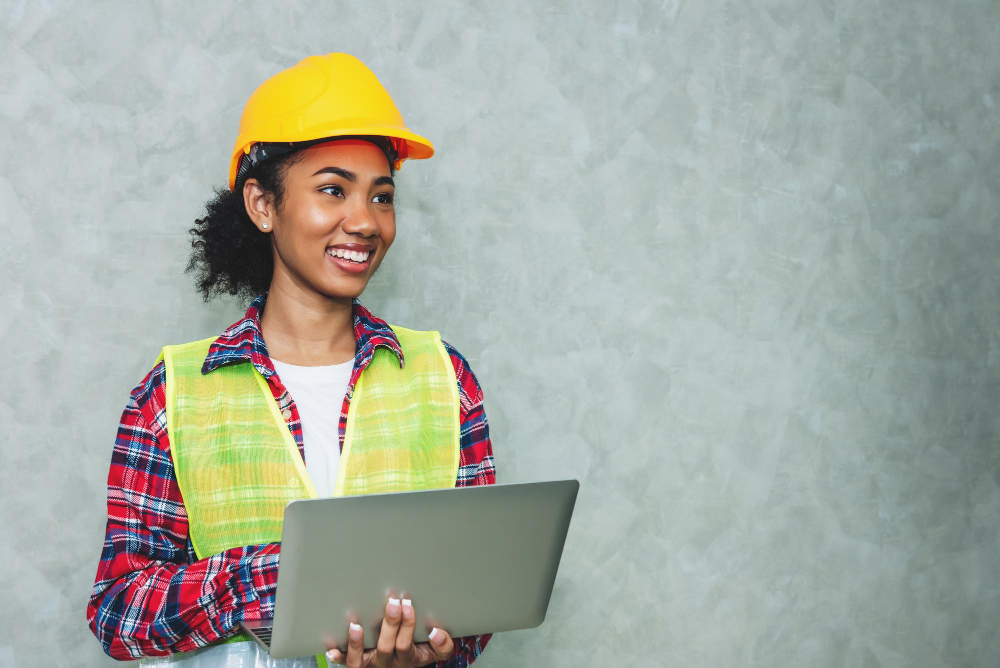 649159a403c9d_portrait-professional-young-black-woman-civil-engineer-architecture-worker-wearing-hard-hat-safety-working-construction-site-warehouseusing-laptop-work (1)